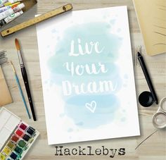 a watercolor painting with the words live your dream written on it and supplies around it