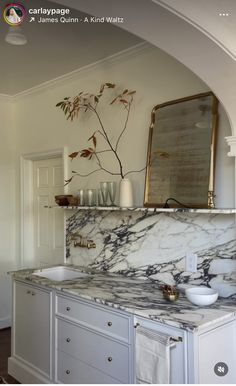 a kitchen with marble counter tops and white cabinets in the center, along with gold accents