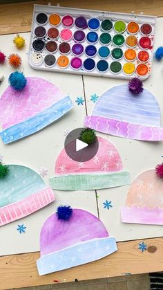 children's winter hats made with watercolors and crayons on a table