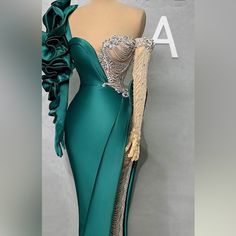 a green gown with ruffled sleeves is displayed on a mannequin's head