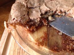 a close up of a pie on a wooden cutting board with a knife in it