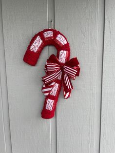 a red and white wreath hanging on the side of a door with ribbon around it