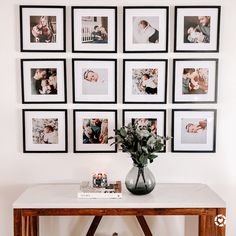 a table with pictures on the wall above it and a vase filled with flowers sitting on top