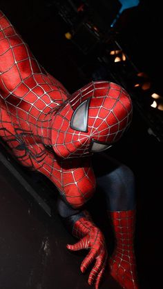 a man in a spiderman costume is posed on the ground with his legs spread out