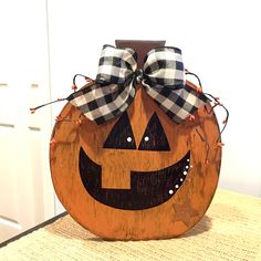 a wooden pumpkin with a black and white checkered bow