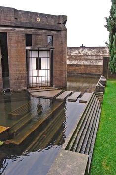 an empty building with water in front of it and grass on the ground next to it