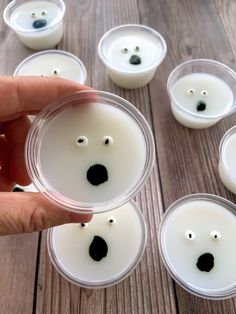 a hand holding a plastic container filled with white candles