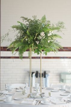 a vase filled with greenery sitting on top of a table next to wine glasses