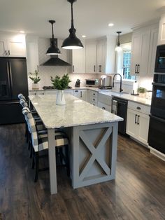 a large kitchen with an island in the middle and black appliances on both sides, along with white cabinets