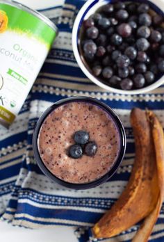 a smoothie with blueberries, bananas and yogurt is on a towel