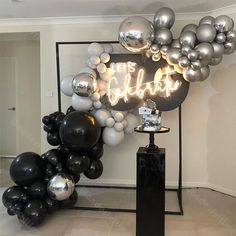 a black and silver balloon arch with the word cheers on it