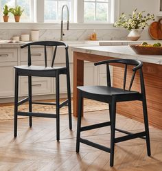 two black chairs sitting in front of a kitchen counter