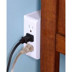 an electrical outlet plugged in to a wall with a wooden cabinet and blue walls