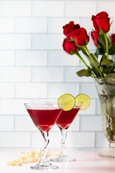 two martini glasses filled with red wine and garnished with lemons, sitting on a counter