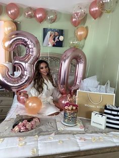 a woman sitting on top of a bed with balloons in the shape of number thirteen