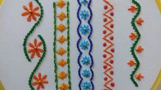 a close up of a embroidery design on a white cloth with orange, blue, and green trimmings