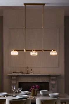 a dining room table with white chairs and plates on it, next to a fireplace