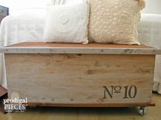 a wooden crate sitting on top of a hard wood floor next to a white bed