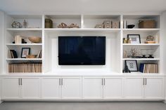 a white entertainment center with shelves and a flat screen tv mounted on it's side