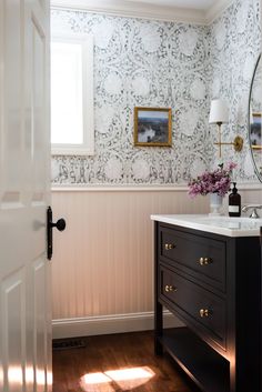 a bathroom with white walls and wood flooring next to a mirror on the wall