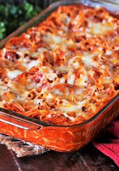 a casserole dish with meat and cheese in it sitting on a table next to a red towel