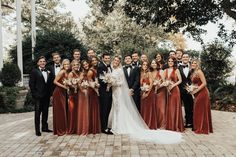 a group of people standing next to each other on a brick floored area with trees in the background