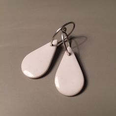 Simple, geometric earrings made of porcelain and white, glazing enamel. Drops measure approx. 2.5x1.5cm and sterling silver rings approx. 1.5cm. Boucles d'oreilles blanches, simples et originales en porcelaine émaillée. Les gouttes mesurent env. 2.5x1.5cm et sont montées sur des anneaux en argent véritable de 1.5cm de diamètre env. Modern Everyday Enamel Jewelry, Modern White Enamel Jewelry, Modern White Everyday Jewelry, White Hypoallergenic Enamel Earrings, White Modern Drop Earrings, Hypoallergenic White Enamel Earrings, Modern White Drop Earrings, Simple Nickel-free White Jewelry, Simple White Nickel-free Jewelry