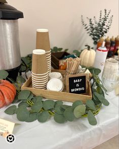 there is a tray with paper cups and plates on it, along with greenery