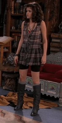 the young woman is standing in her living room wearing knee high boots and a plaid dress