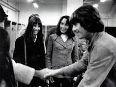 black and white photograph of three women shaking hands with one another in an office building