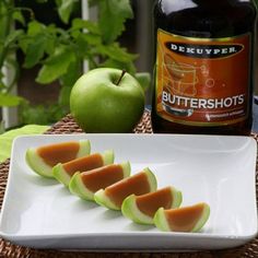 slices of melon on a white plate next to a bottle of buttershots