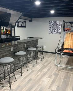 an empty bar with stools and barstools in a basement area that has wood flooring