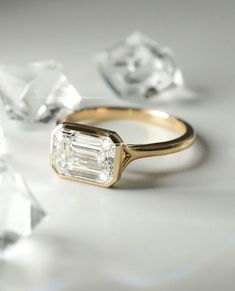 an engagement ring surrounded by diamonds on a white surface