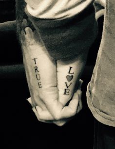 two people with tattoos on their arms holding each other's hands and the words true love written on them