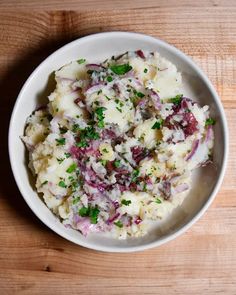 a white bowl filled with mashed potatoes and garnished with chopped parsley