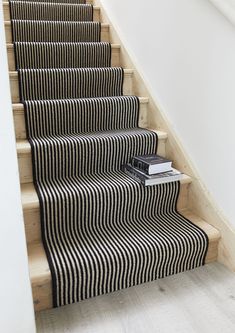 the stairs are lined with black and white striped carpet, along with a book on top