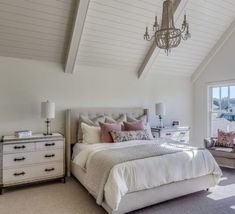 a bedroom with a bed, dresser and chandelier in the middle of it