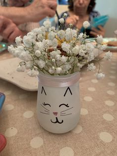 a vase with flowers in it sitting on a table next to an older woman and child