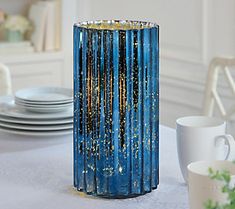 a blue vase sitting on top of a table next to white plates and silverware