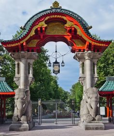 an ornate gate with statues and lamps on it