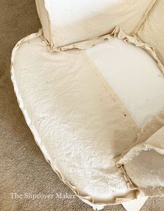 the corner of a chair that has been made out of white fabric and is sitting on carpet