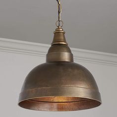 an antique brass pendant light hanging from a ceiling in a room with white walls and trimmings