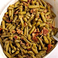 green beans with bacon are in a white bowl on the table, ready to be eaten