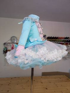 a mannequin wearing a blue and white dress on a wooden table in a room