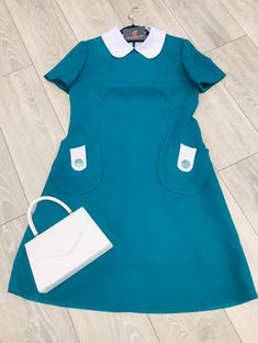 The Sandra:  Is a gorgeous late 1960s style Mod dress is ideal for any occasion, with usable pockets with a contrasting pocket flap and button detail, also has the Peter Pan contrasting collar.  Made up in a lovely Soft Trevira teal fabric, Semi a-line style with zip closure at the back, been cut to a knee length however you can specify a length if you wish.  All of my garments are made to order so your dress can be cut to a specific size, length and or measurements.  Team this up with your fav Classic Collared Dress With Pockets, Retro A-line Vintage Dress For Work, Retro Collared Formal Dress, Vintage A-line Dress With Pockets, Vintage A-line Dresses With Pockets, Retro Dress With Peter Pan Collar And Buttons, 1950s Style Collared Dress For Work, Workwear Dress With Peter Pan Collar And Buttons, Collared Retro Vintage Dress For Work