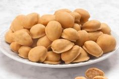 a white plate filled with almonds next to a pile of cashews