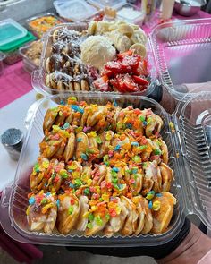 two plastic trays filled with different types of pastries and desserts on top of a table