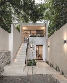 a modern house with stairs leading up to the second floor and trees in front of it