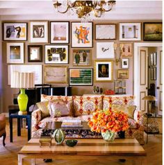 a living room filled with furniture and lots of pictures on the wall above it's coffee table