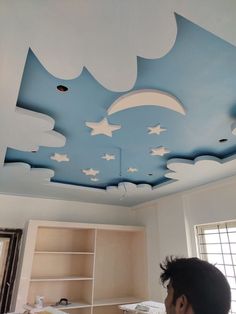 a man is looking up at the sky painted on the ceiling above his bed in this bedroom